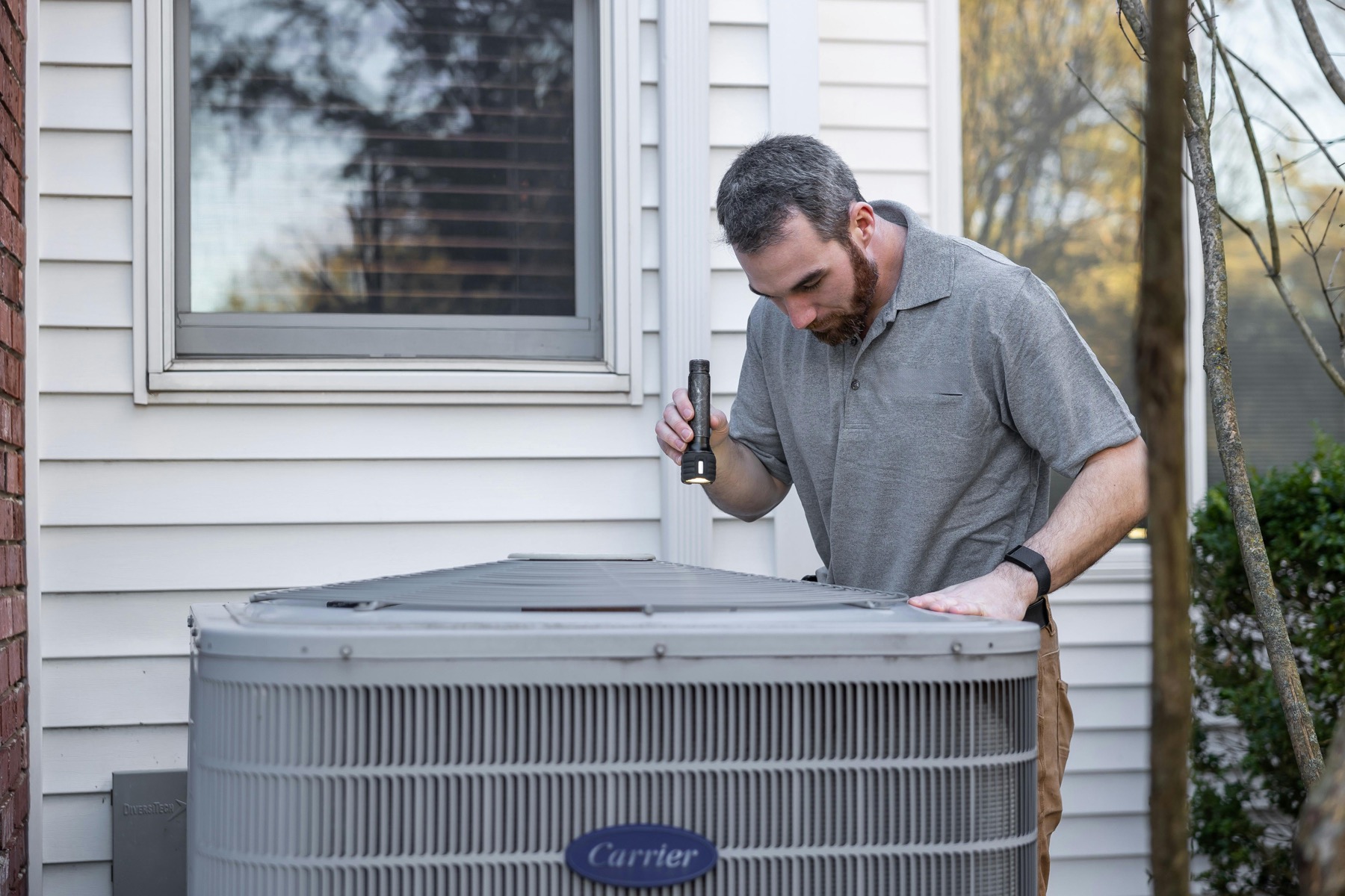 Technician inspecting an outdoor residential HVAC unit